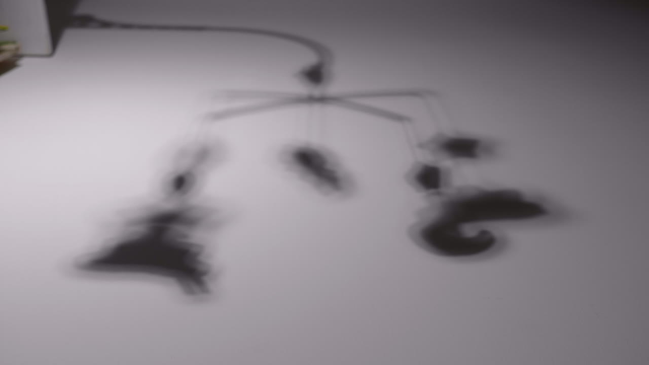 Blurry Shadow Of Baby Toy Hang Over The Crib In The Room