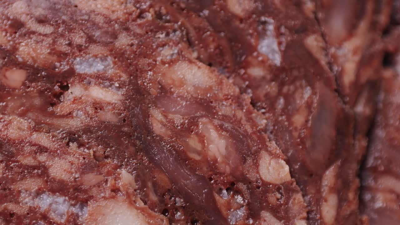 black bull sausage ham, tongue pork dry-cured sausage on a black background, traditional spanish delicatessen food, close up.