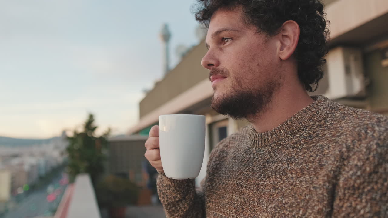 Man drinking coffee on balcony with city view