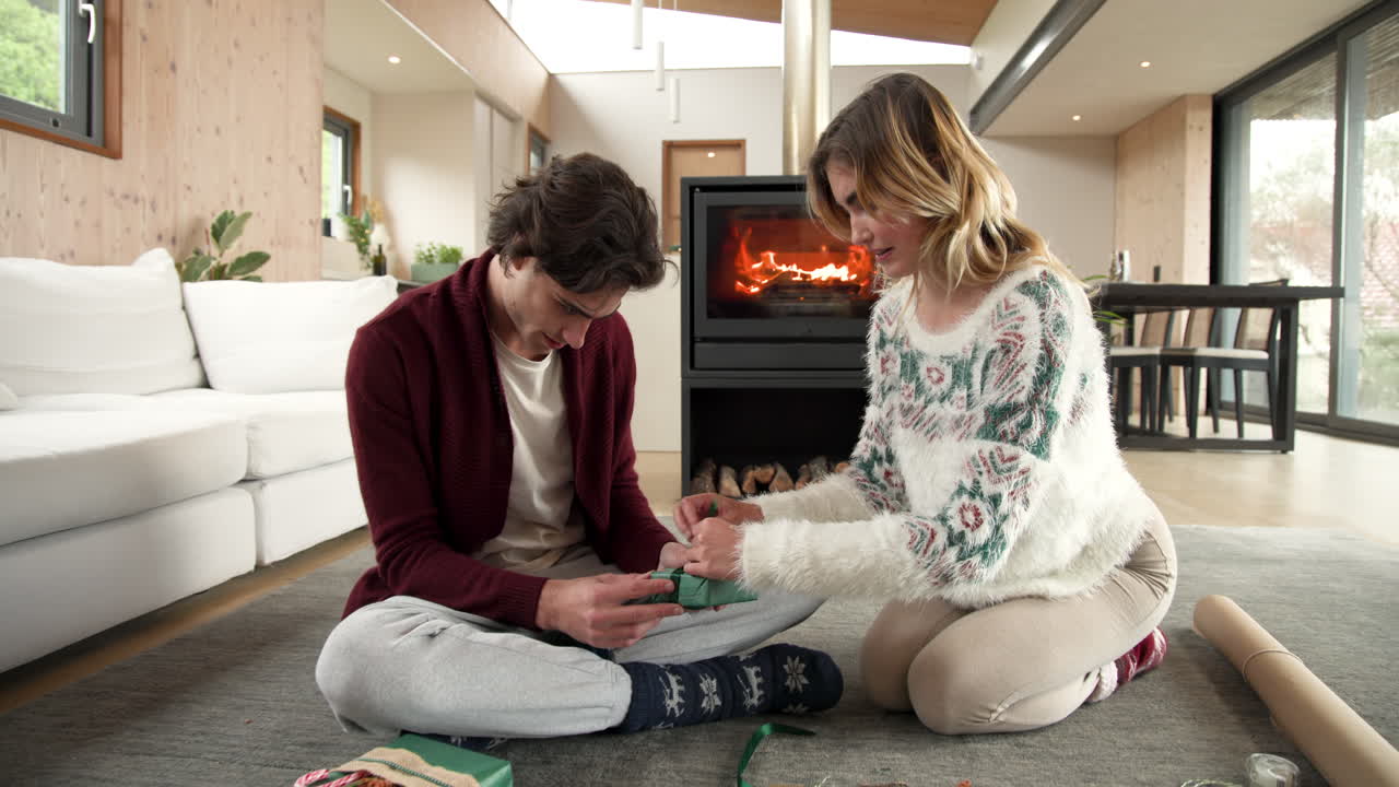 Wrapping Christmas gifts by fireplace, couple sharing cozy holiday atmosphere together