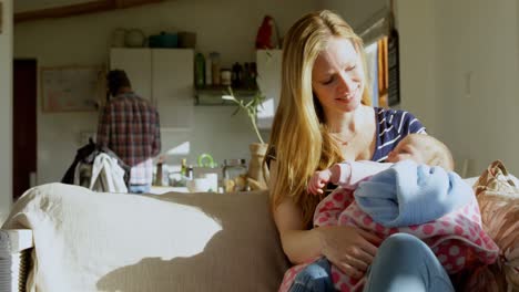 Vista-Frontal-De-Una-Feliz-Madre-Caucásica-Adulta-Mirando-Al-Bebé-Y-Sentada-En-El-Sofá-En-Casa-4k