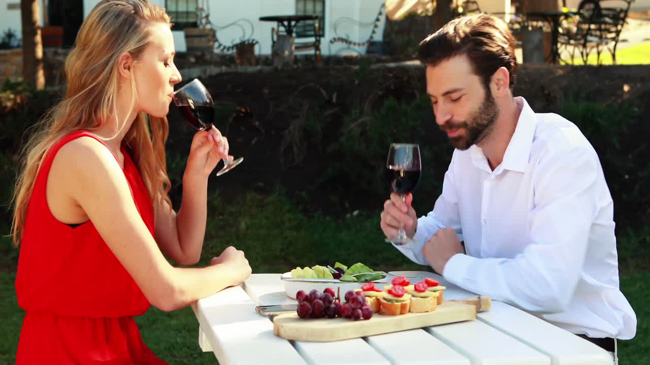 Coppia brinda con bicchieri di vino in ristorante all'aperto 4k