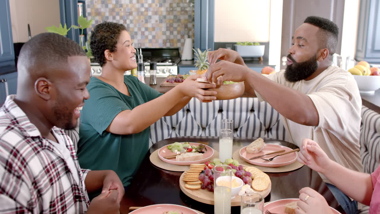 Sharing salad, diverse friends enjoying meal together at home dining table