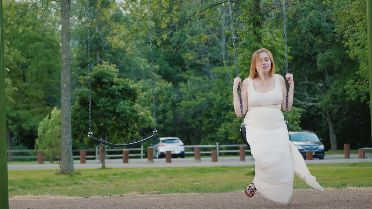 공원에서 그네를 타는 젊은 임산부