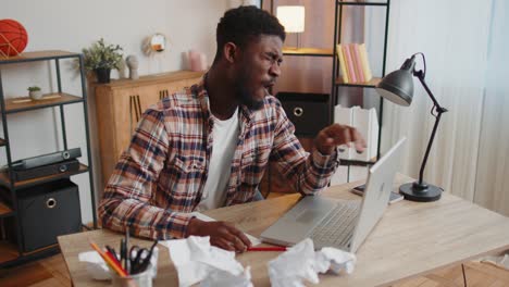 tired man at home office falling asleep on table with laptop computer crumpled sheets of paper
