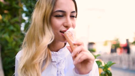 Slow-Motion:Young-beautiful-girl-eats-ice-cream-while-sitting-at-street-in-Europe