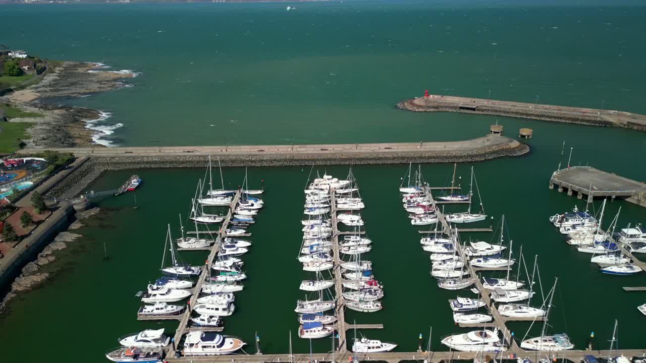 Toma aérea, comenzando por la derecha y moviéndose hacia la izquierda para revelar barcos en un puerto deportivo en un día soleado