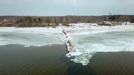 vista de pájaro en el muelle congelado y cubierto de nieve - orilla del mar en el frío día de invierno