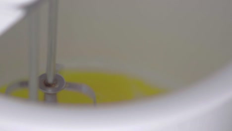 slow-motion closeup of a mixer's whisk mixing a batter while preparing a cake