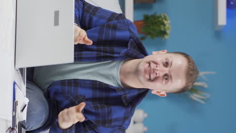 Vertical-video-of-Home-office-worker-man-making-cute-gesture-at-camera.