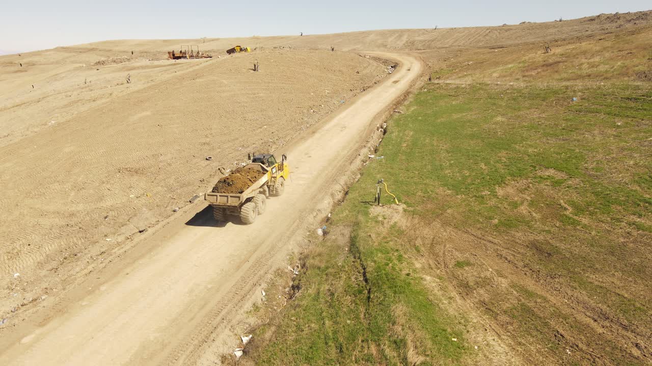 желтый тяжелый мощный самосвал перевозит грунт в гору, вид с воздуха с беспилотника