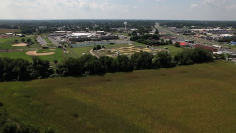 An-aerial-view-of-an-open-green-field-next-to-an-empty,-curved-road