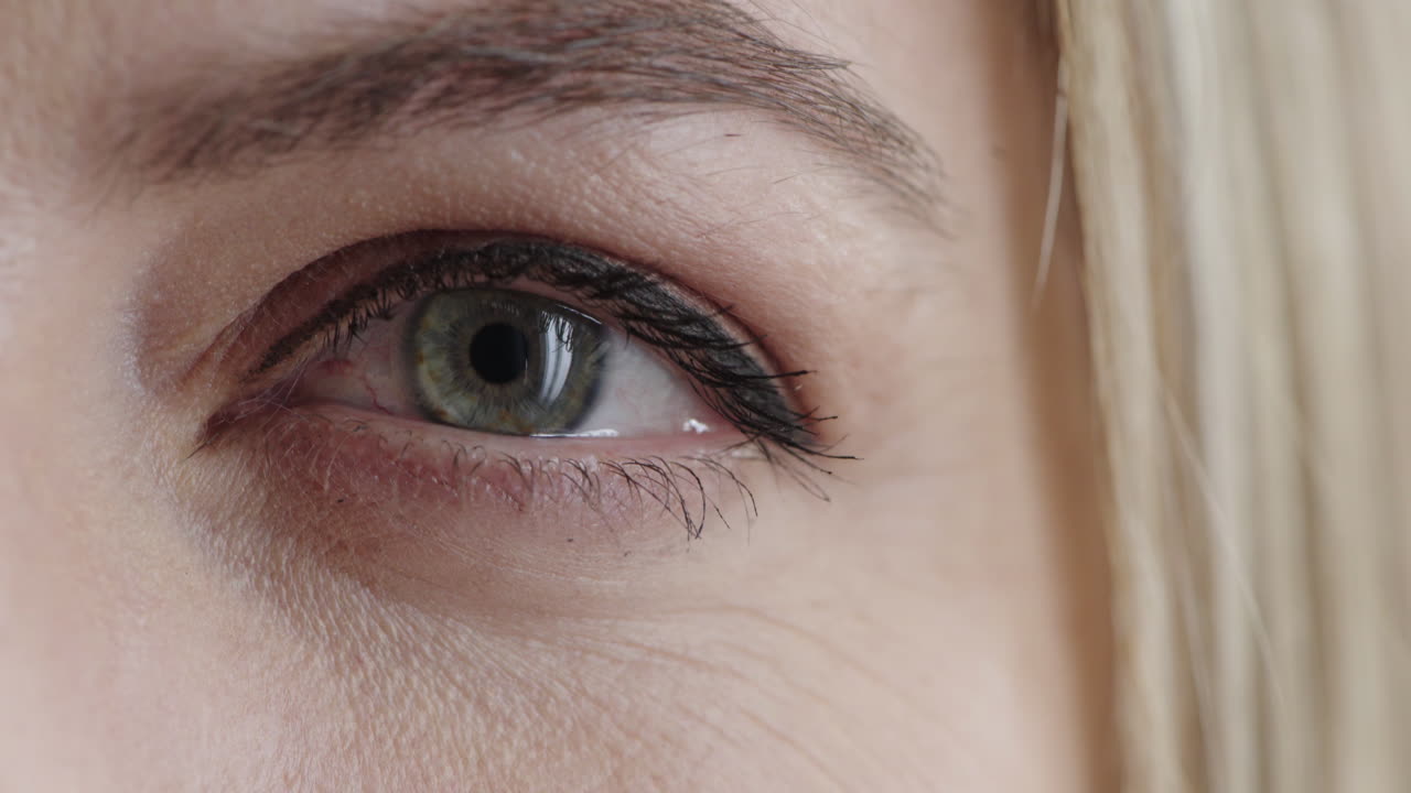 mujer de cerca abriendo el ojo azul mirando el detalle del iris de la cámara