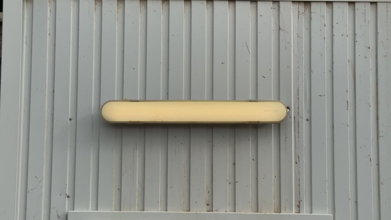 Lamp Emitting a Flickering Yellow Light on the Metal Container Wall