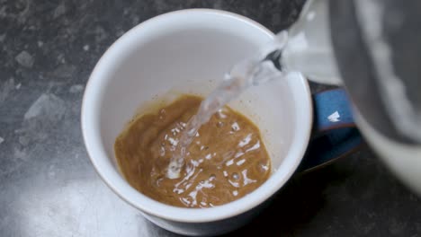 vertiendo agua caliente en una taza de café instantáneo en cámara lenta