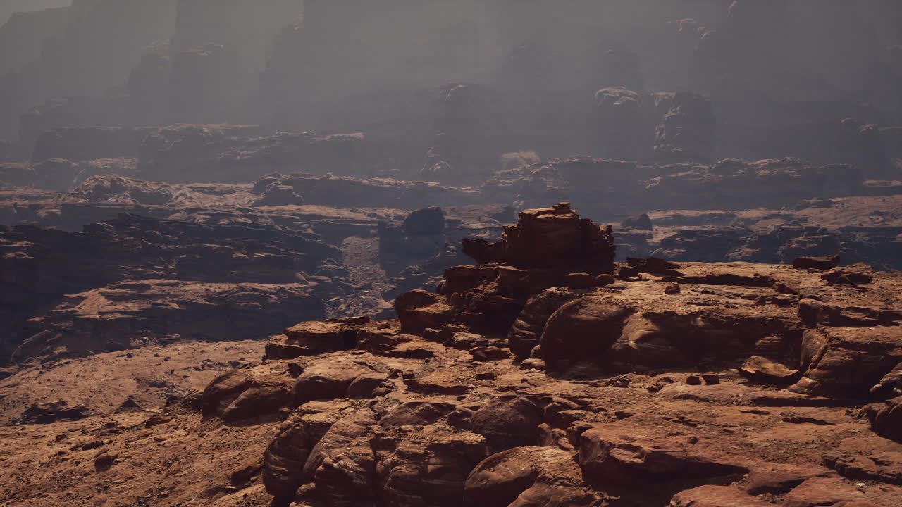 un cañón brumoso con formaciones rocosas rojas