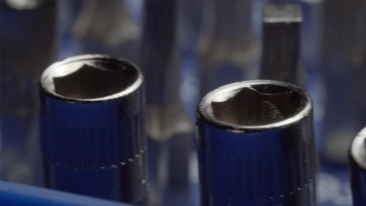 Close up panning over blue screwdriver kit components showing textured handles metal tips and detailed tool surfaces against a blurred background