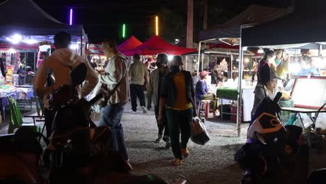 personas caminando e interactuando en un mercado nocturno