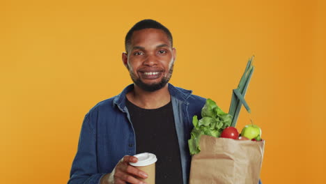 Relaxed-carefree-person-drinking-a-coffee-cup-and-carrying-his-groceries