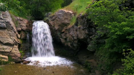 Una-Cámara-Lenta-De-Drones-Empuja-Una-Cascada-En-Medio-Del-Cañón-De-Adams-En-Un-Hermoso-Día-De-Primavera-Destacando-Los-árboles-Verdes-A-Su-Alrededor