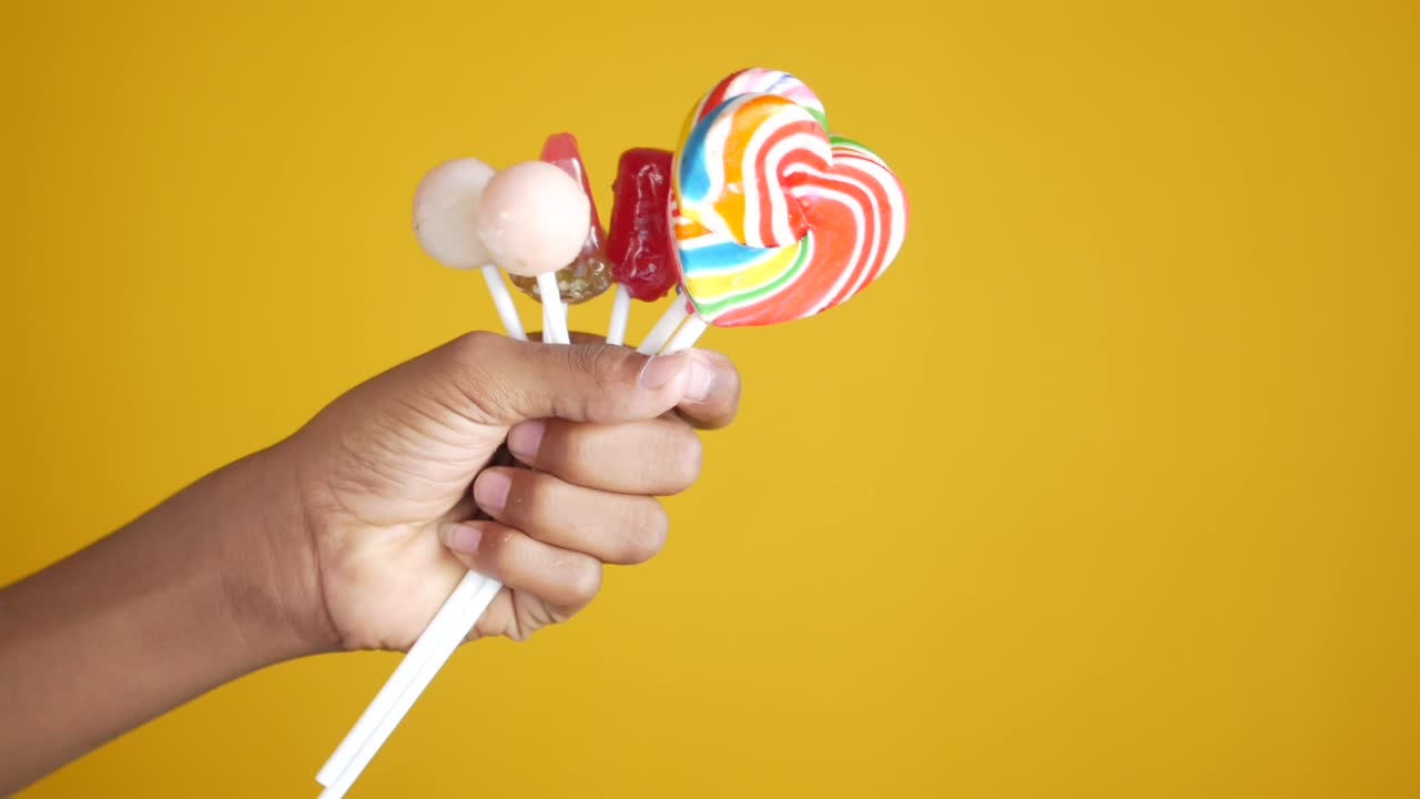노란색 배경 에 릴리 사탕 을 들고 있는 손
