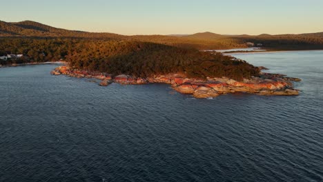 orbit shot of fires bay, iconic orange colored granite rocks, tasmania at sunset, australia