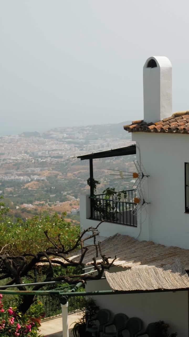 Traditional whitewashed Andalusian house with terracotta roof tiles and balcony overlooks coastal city