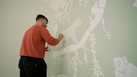 the artist is decorating walls by drawings in the children's room. art painting of the walls in the new house. repair works.