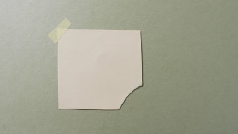 une vidéo en gros plan d'un morceau de papier blanc déchiré collé sur fond vert.