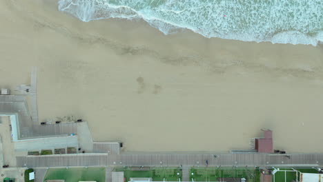 Beach-aerial-view,-shoreline,-waves,-promenade