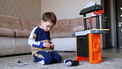 kid with toy kitchen at home. a young child sits on the floor assembling a colorful toy kitchen set in a living room during daylight hours