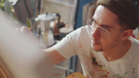 young creative man painting picture in art studio