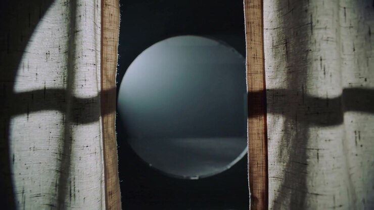 Seam widening causing heavy beige curtains showing round lit disc on dark stage with shadow band