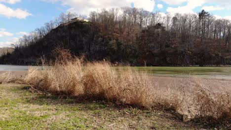 Fly-by-over-bench-towards-river-and-brush