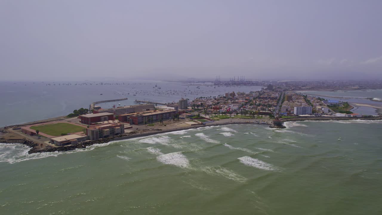 Veduta aerea di una città costiera con un porto trafficato e onde che si infrangono