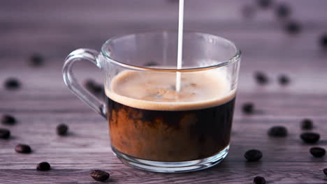 milk being poured into a cup of black coffee