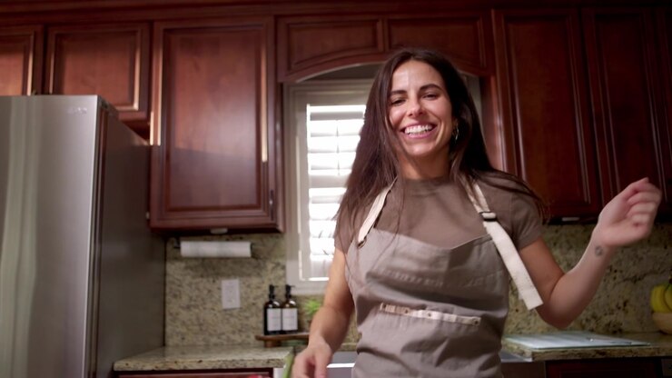 Donna guarda la telecamera e balla mentre cucina.
