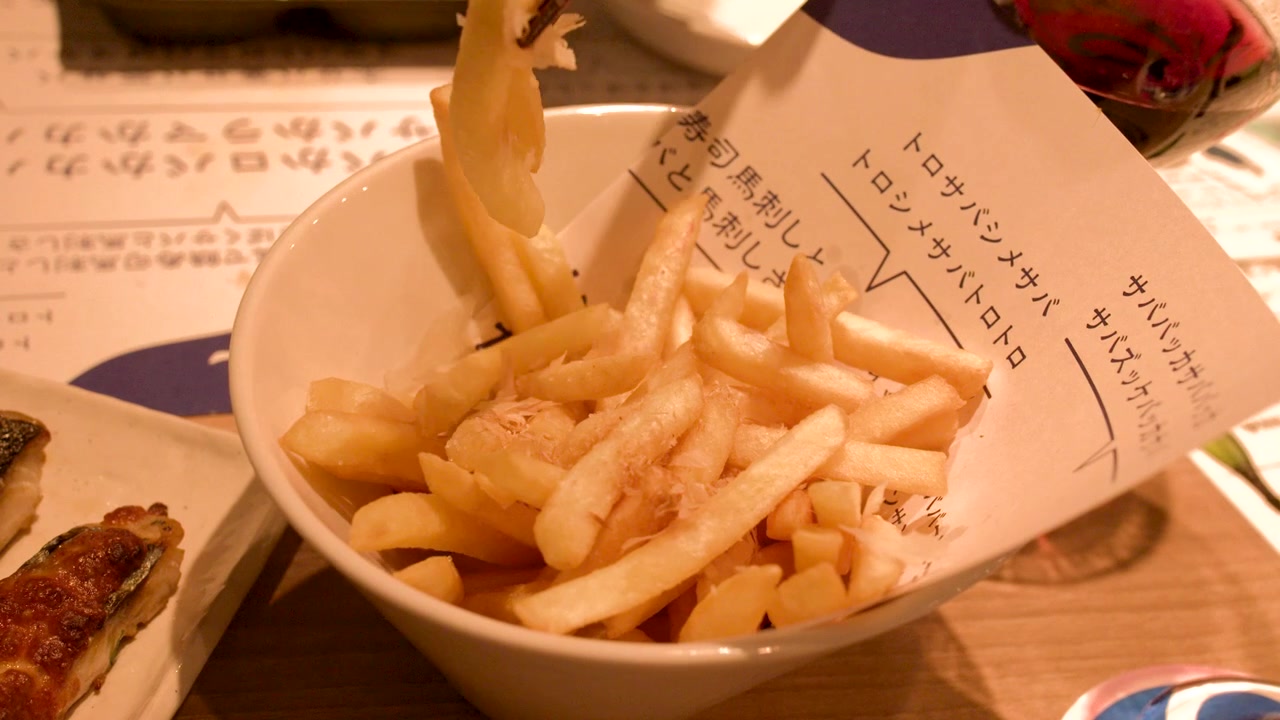 Close-up shot of chopsticks picking up french fries from a bowl in a Japanese restaurant
