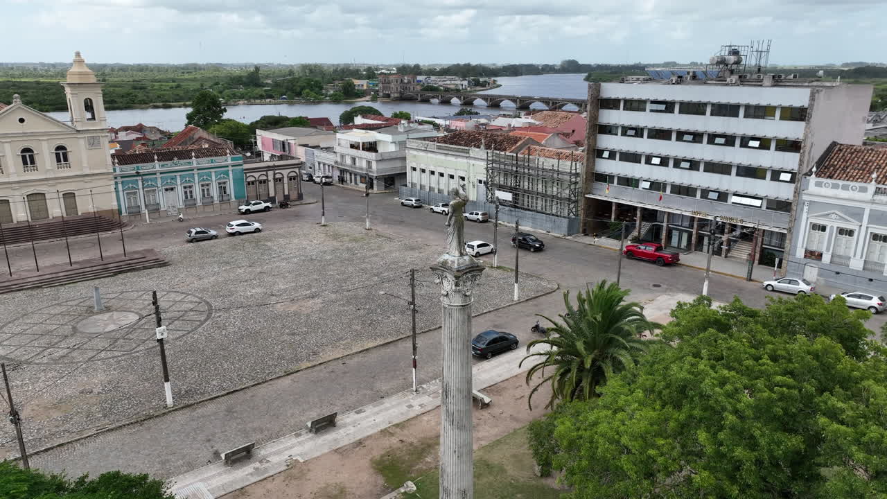 Rallentatore ravvicinato della statua storica nella piazza centrale di Jaguarao, in Brasile, con la chiesa della città e il ponte internazionale all'orizzonte