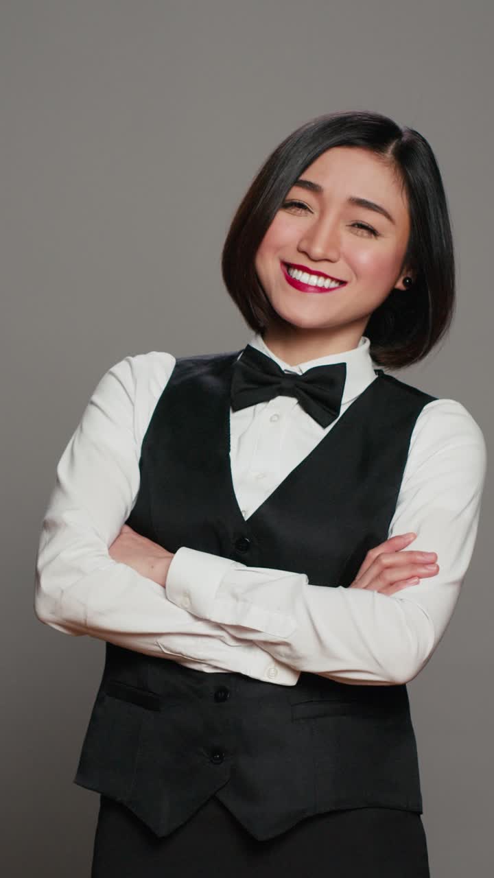 Video verticale: concierge asiatica in un hotel, indossa un'elegante uniforme con fiocco