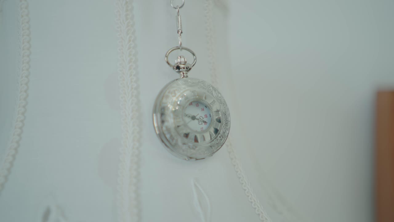reloj de bolsillo plateado vintage colgado sobre una suave tela blanca