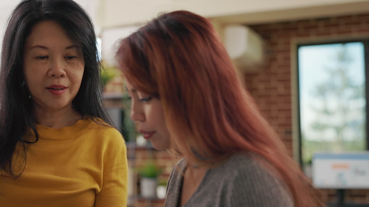 Team of asian women analyzing graphs on paper and tablet