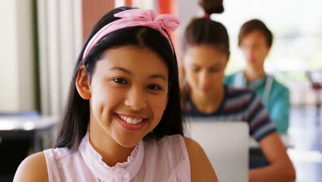 Portrait-of-smiling-schoolgirl-studying-in-classroom