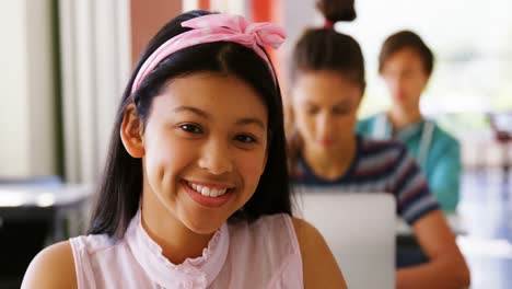 portrait of smiling schoolgirl studying in classroom