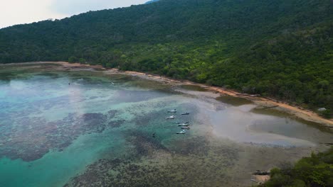 reverse-dolly-aerial-view-of-fishing-boats-moored-at-sea-during-low-tide-in-the-beautiful-Karimunjawa-Island,-Central-Java---Indonesia