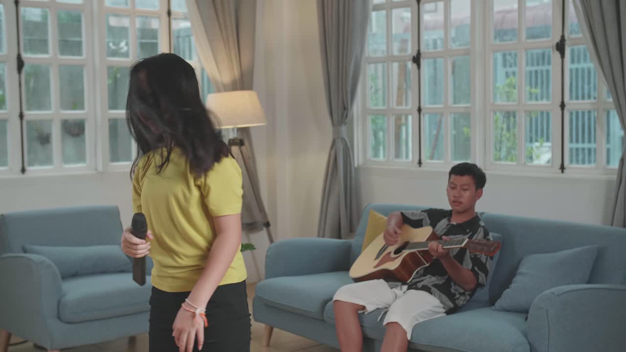 Asian Boy Playing Guitar And Girl Singing Rock Music At Home