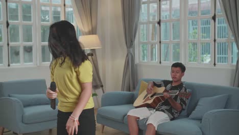 asian boy playing guitar and girl singing rock music at home