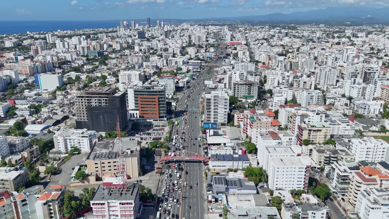 Establishing aerial view of 27 de Febrero Avenue in downtown Santo Domingo, Dominican Republic. Dolly in drone footage