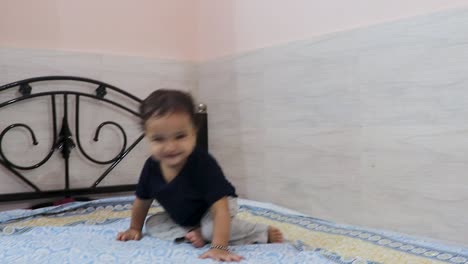 cute toddler baby boy trying to stand for the first time at bed at home