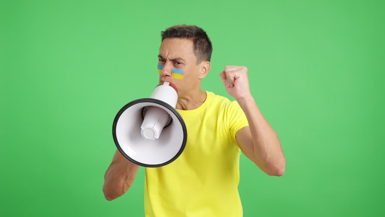 Excited man with ukrainian flag on face using a megaphone